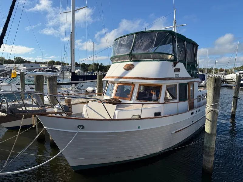 The Image of A 1981 Marine Trader Double Cabin docked at a marina. It features a green canopy and wooden accents. - 0
