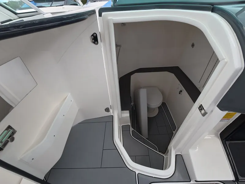 Slide: The Image of The 2021 Aviara AV32 OB features a compact onboard toilet with gray tiles and white walls. - 18