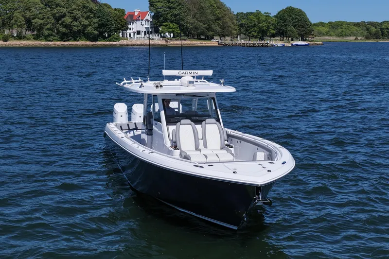 Slide: The Image of 2026 Everglades 395 Center Console boat on water near shoreline with trees and house. - 11