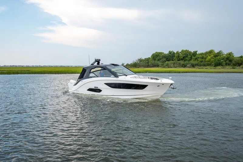 Slide: The Image of A sleek white motorboat cruising on calm water, surrounded by green landscape. - 0
