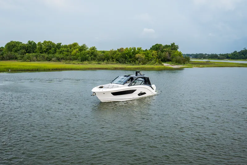 Slide: The Image of 2026 Sea Ray Sundancer 370 Outboard on calm water, surrounded by green landscape. - 2
