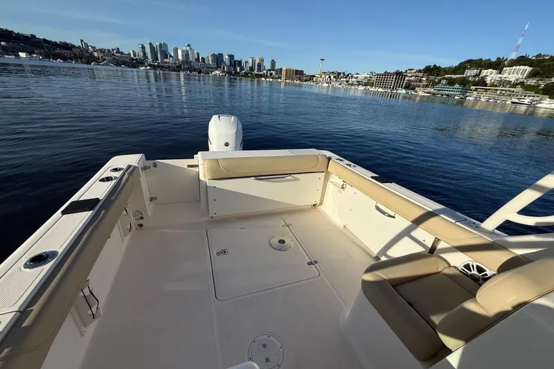Slide: The Image of 2016 Pursuit DC 265 Dual Console boat on calm water with city skyline view. - 10