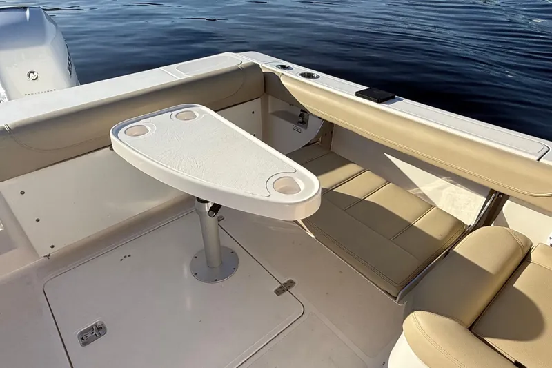 Slide: The Image of 2016 Pursuit DC 265 Dual Console boat interior with seating and table on calm water. - 13
