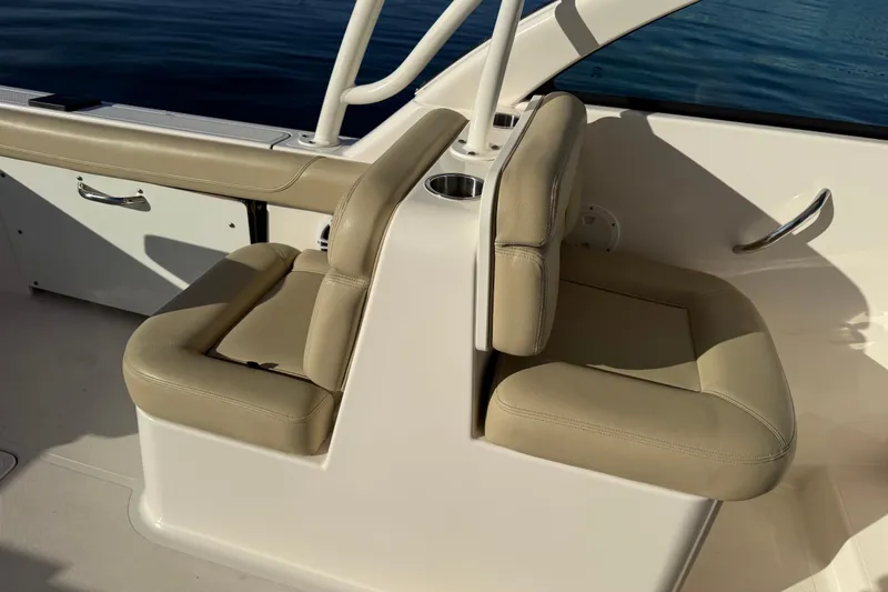 Slide: The Image of 2016 Pursuit DC 265 Dual Console boat interior with beige seating and cup holder. - 14