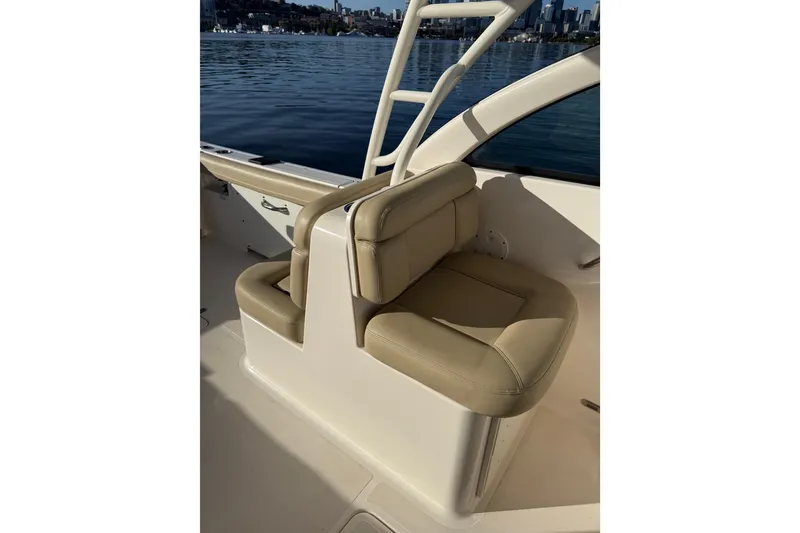 Slide: The Image of 2016 Pursuit DC 265 Dual Console boat interior with beige seating and water view. - 15