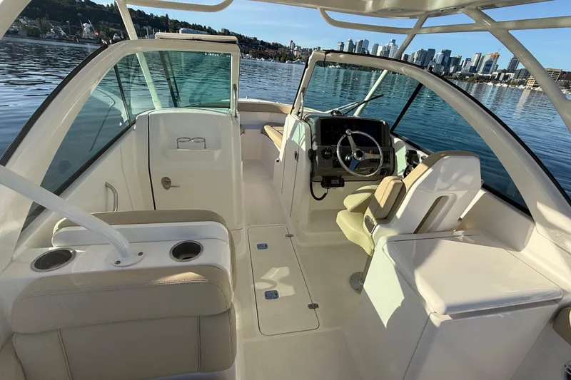 Slide: The Image of 2016 Pursuit DC 265 Dual Console boat interior with steering wheel, seating, and city skyline view. - 16