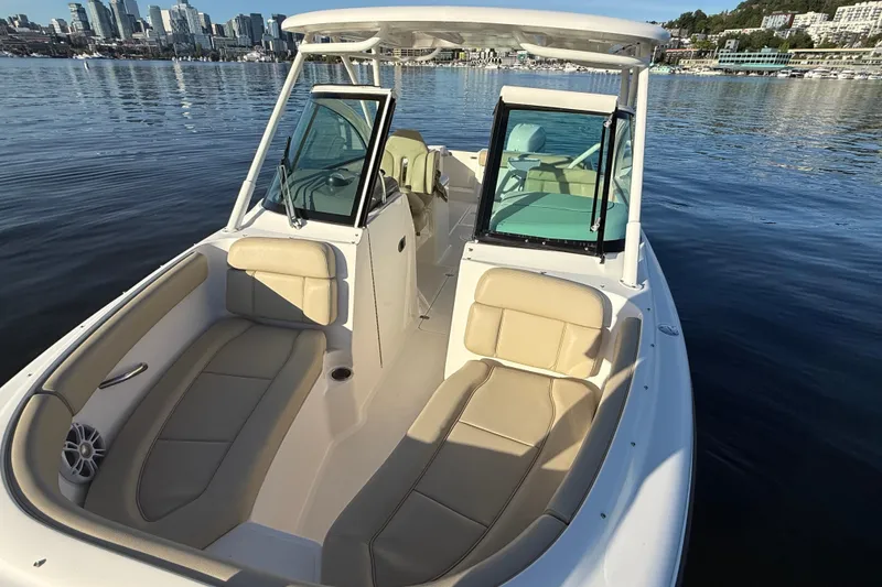 Slide: The Image of 2016 Pursuit DC 265 Dual Console boat on calm water with city skyline backdrop. - 19