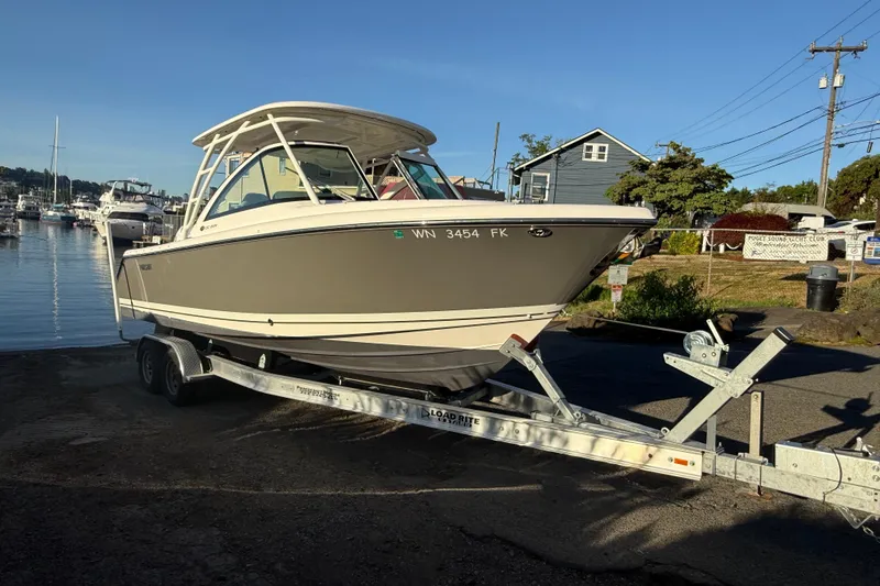 Slide: The Image of 2016 Pursuit DC 265 Dual Console boat on trailer at marina, sunny day. - 2