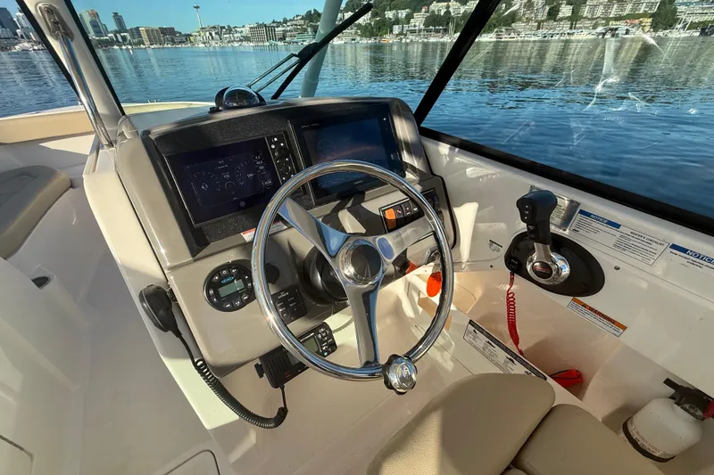 Slide: The Image of 2016 Pursuit DC 265 Dual Console boat cockpit with steering wheel and control panel. - 21