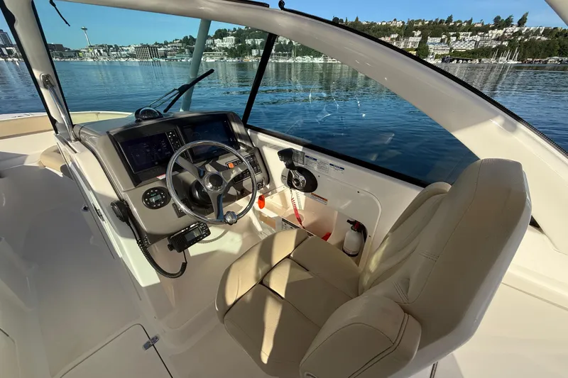 Slide: The Image of 2016 Pursuit DC 265 Dual Console boat interior with steering wheel and dashboard on a sunny day. - 22