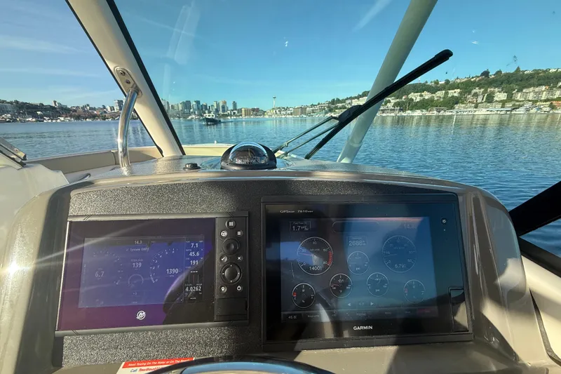 Slide: The Image of Helm view of 2016 Pursuit DC 265 Dual Console boat with city skyline in background. - 23