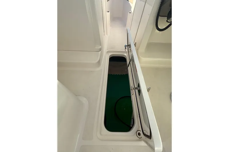 Slide: The Image of 2016 Pursuit DC 265 Dual Console boat storage compartment open, showcasing interior space. - 26