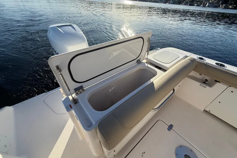 Slide: The Image of 2016 Pursuit DC 265 Dual Console boat with open storage compartment on calm water. - 7