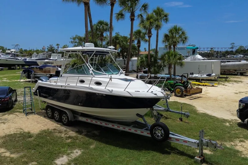 Slide: The Image of 2018 Robalo R305 Walkaround boat on trailer, parked near palm trees and marina. - 1