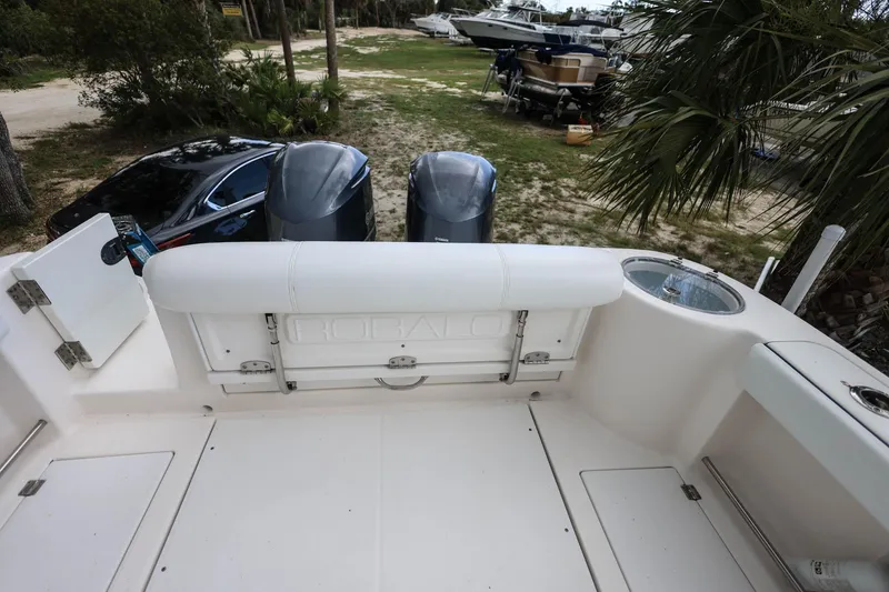 Slide: The Image of 2018 Robalo R305 Walkaround boat with dual engines, parked near trees and vehicles. - 11