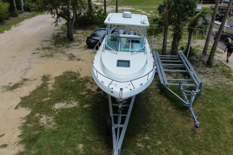 Slide: The Image of 2018 Robalo R305 Walkaround boat on trailer, parked on grassy area near trees. - 2