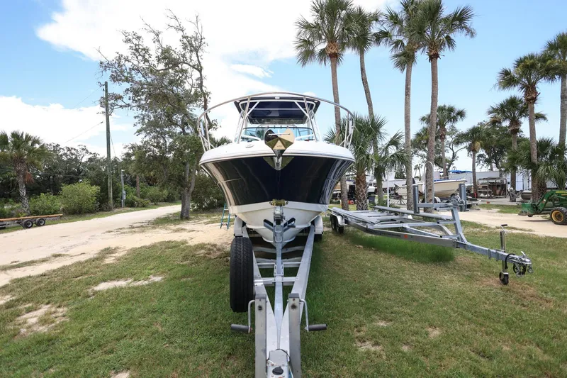 Slide: The Image of 2018 Robalo R305 Walkaround boat on trailer, surrounded by palm trees and greenery. - 3