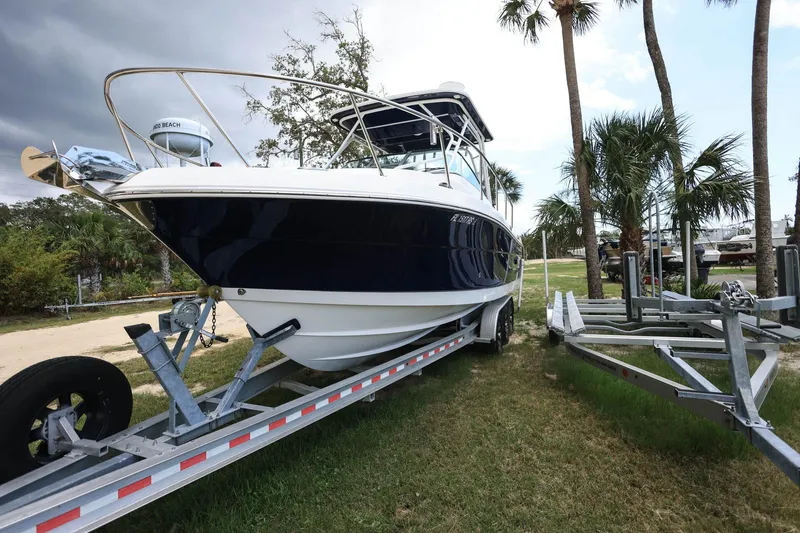 Slide: The Image of 2018 Robalo R305 Walkaround boat on trailer, surrounded by palm trees and cloudy sky. - 4