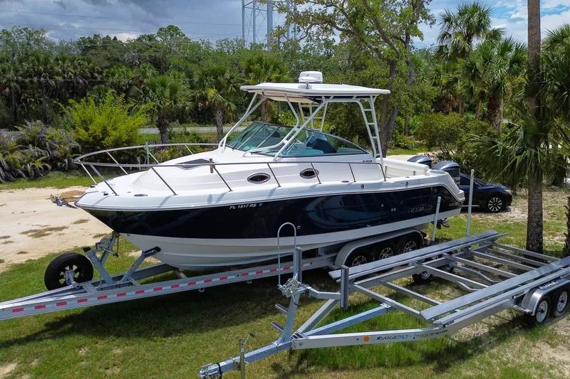 Slide: The Image of 2018 Robalo R305 Walkaround boat on trailer, surrounded by lush greenery. - 5