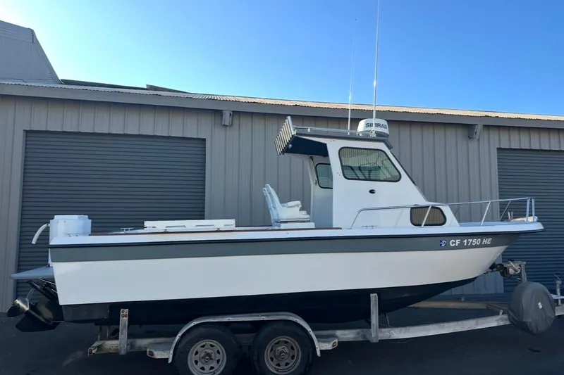 Slide: The Image of 1986 Radon 21 Sport boat on trailer, parked near a metal building. - 0