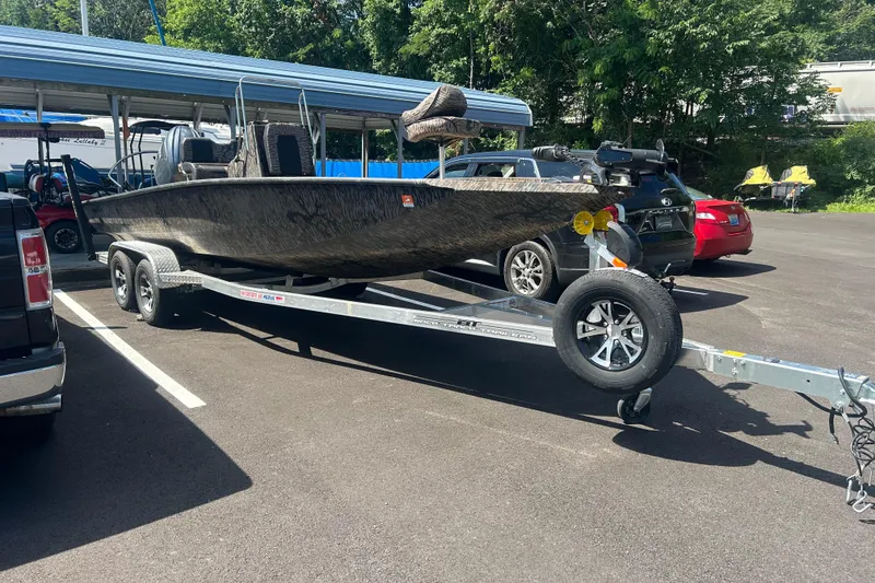 Slide: The Image of 2025 Xpress H22B Bay boat on trailer in parking lot, surrounded by cars. - 13