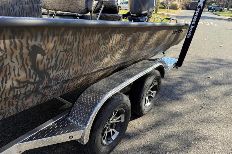 Slide: The Image of 2025 Xpress H22B Bay boat on trailer with camouflage design and dual wheels. - 2