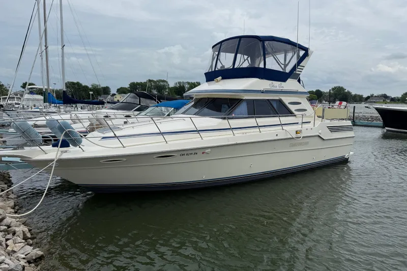 The Image of 1986 Sea Ray 410 Aft Cabin yacht docked in a marina, featuring a blue canopy. - 1