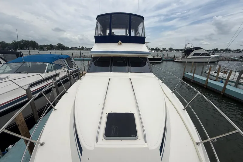 Slide: The Image of 1986 Sea Ray 410 Aft Cabin yacht docked at marina, showcasing spacious deck and cabin. - 11