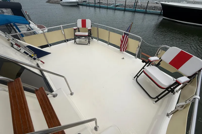 Slide: The Image of 1986 Sea Ray 410 Aft Cabin deck with chairs and American flag, docked at marina. - 12