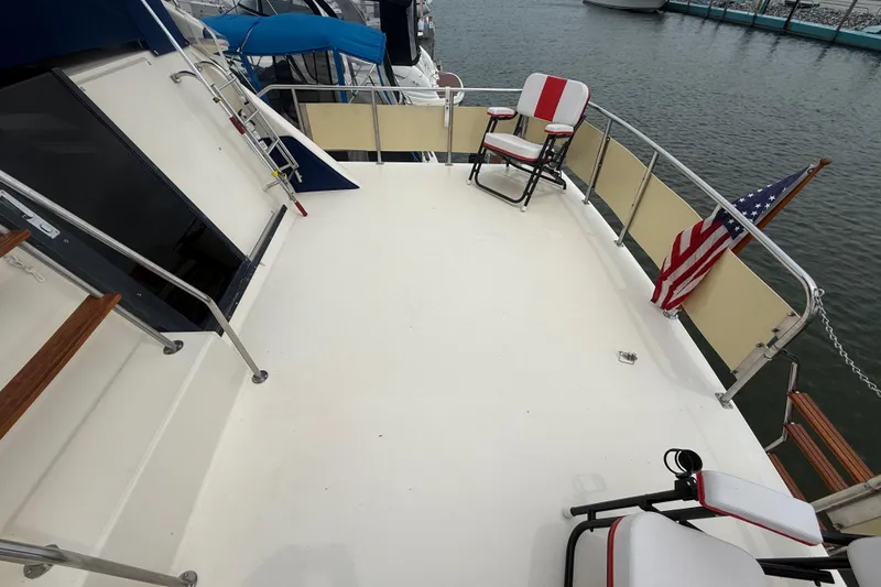 Slide: The Image of 1986 Sea Ray 410 Aft Cabin deck with chairs and American flag, docked at marina. - 13