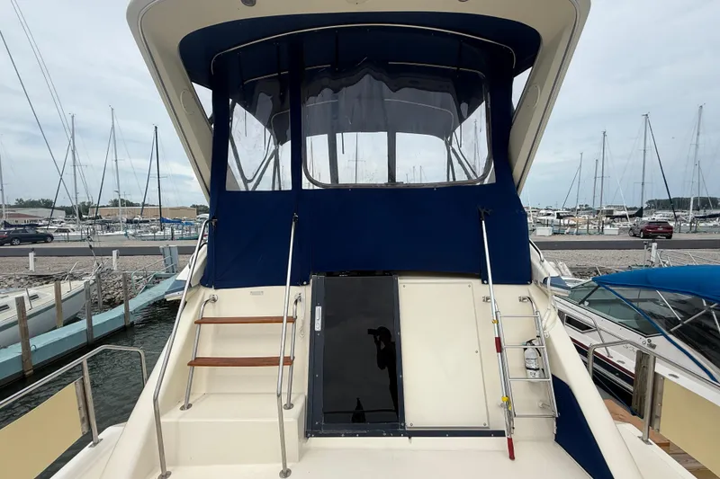 Slide: The Image of 1986 Sea Ray 410 Aft Cabin yacht docked at marina, featuring blue canopy and wooden steps. - 14