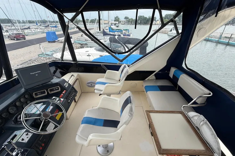 Slide: The Image of 1986 Sea Ray 410 Aft Cabin boat interior with helm, seating, and marina view. - 19