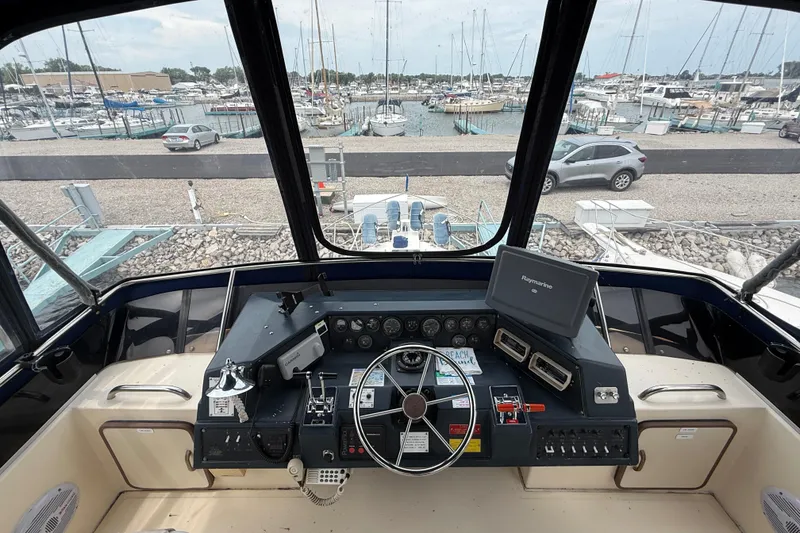 Slide: The Image of 1986 Sea Ray 410 Aft Cabin helm with marina view, featuring navigation equipment and steering wheel. - 22