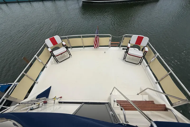 Slide: The Image of 1986 Sea Ray 410 Aft Cabin deck with chairs and American flag on calm water. - 30