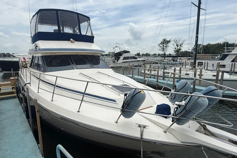 Slide: The Image of 1986 Sea Ray 410 Aft Cabin yacht docked at marina, featuring spacious deck and cabin. - 4