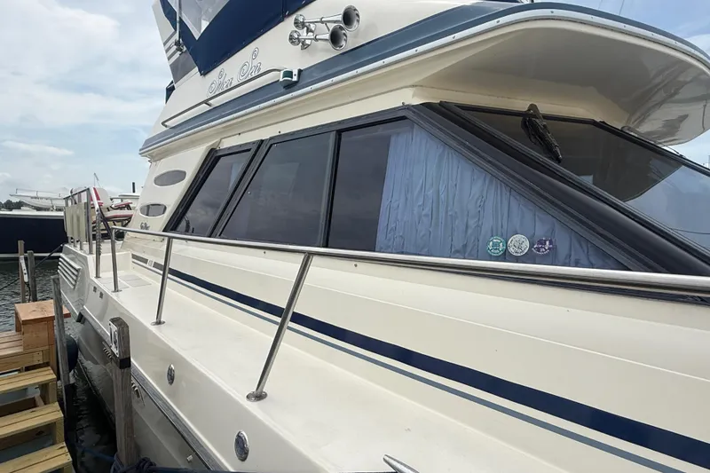 Slide: The Image of 1986 Sea Ray 410 Aft Cabin yacht docked, showcasing sleek design and spacious windows. - 5