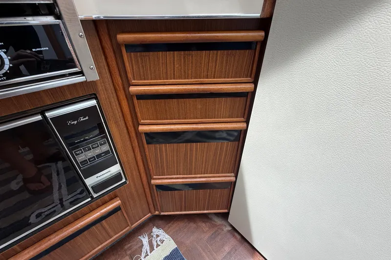 Slide: The Image of 1986 Sea Ray 410 Aft Cabin interior with wood cabinetry and Panasonic microwave. - 52