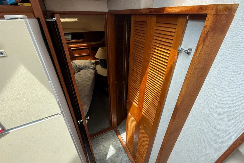 Slide: The Image of 1986 Sea Ray 410 Aft Cabin interior with wooden doors and cozy bedroom. - 54