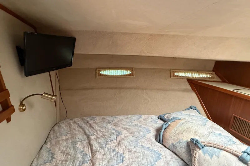 Slide: The Image of Cozy cabin interior of 1986 Sea Ray 410 Aft Cabin with bed and mounted TV. - 56