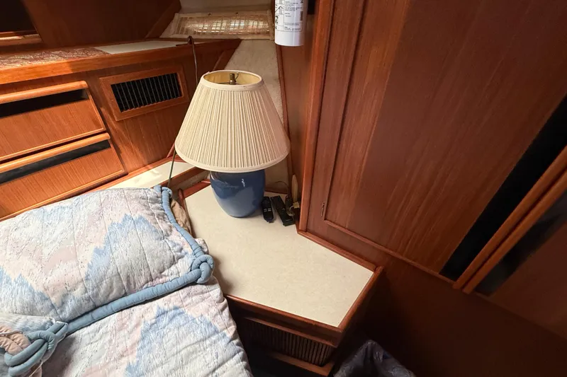 Slide: The Image of 1986 Sea Ray 410 Aft Cabin interior with lamp, bedding, and wooden cabinetry. - 59