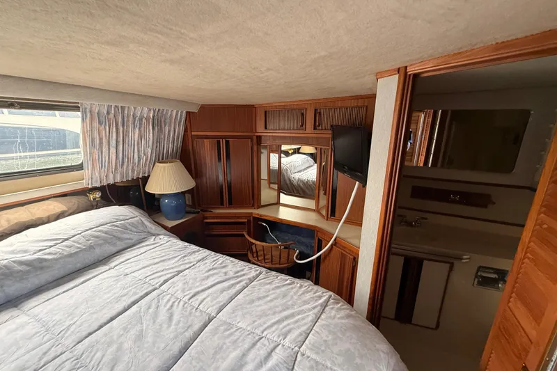Slide: The Image of 1986 Sea Ray 410 Aft Cabin interior with bed, wooden cabinetry, and vanity area. - 67