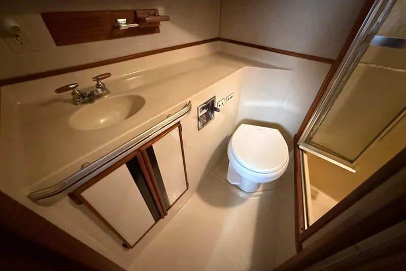 Slide: The Image of 1986 Sea Ray 410 Aft Cabin bathroom with sink, toilet, and shower. - 75