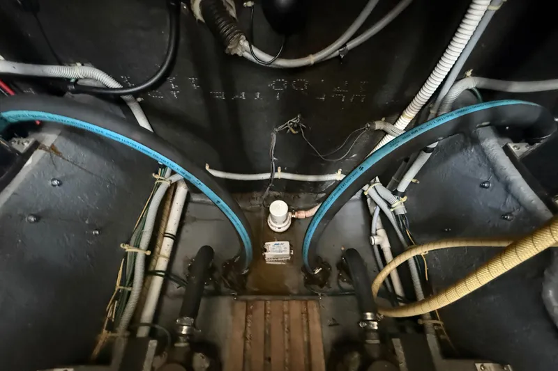 Slide: The Image of Engine room of 1986 Sea Ray 410 Aft Cabin with visible hoses and wiring. - 83