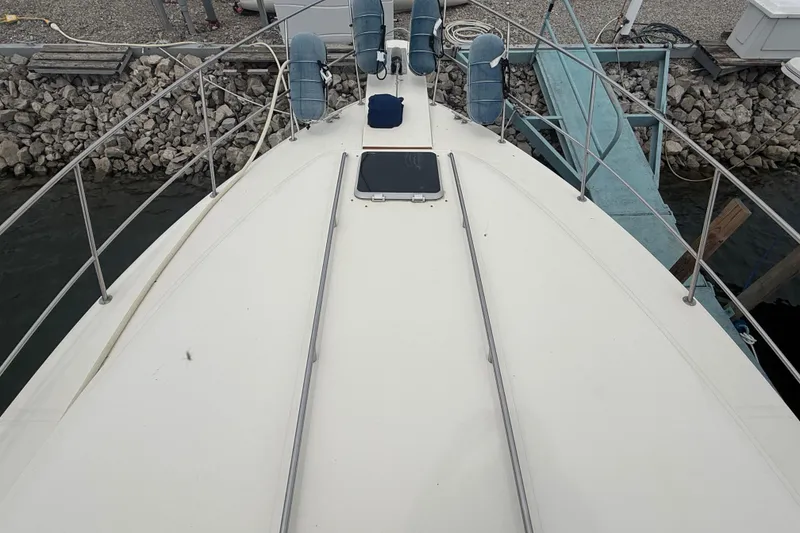 Slide: The Image of 1986 Sea Ray 410 Aft Cabin yacht deck view, docked near rocky shoreline. - 9