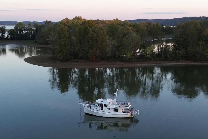 Slide: The Image of Kadey-Krogen 39 boat from 2001 anchored on a serene lake with lush trees. - 1