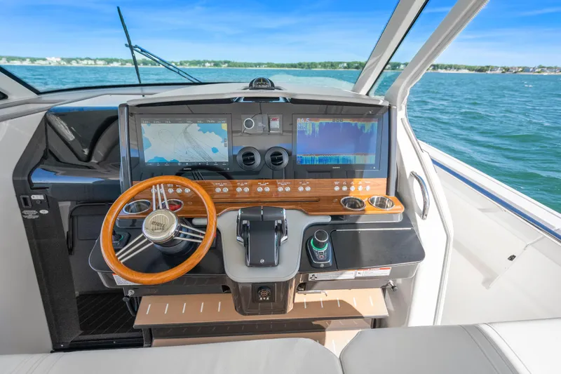 Slide: The Image of 2024 Tiara Yachts 43 LS helm with advanced navigation displays and wooden steering wheel. - 21