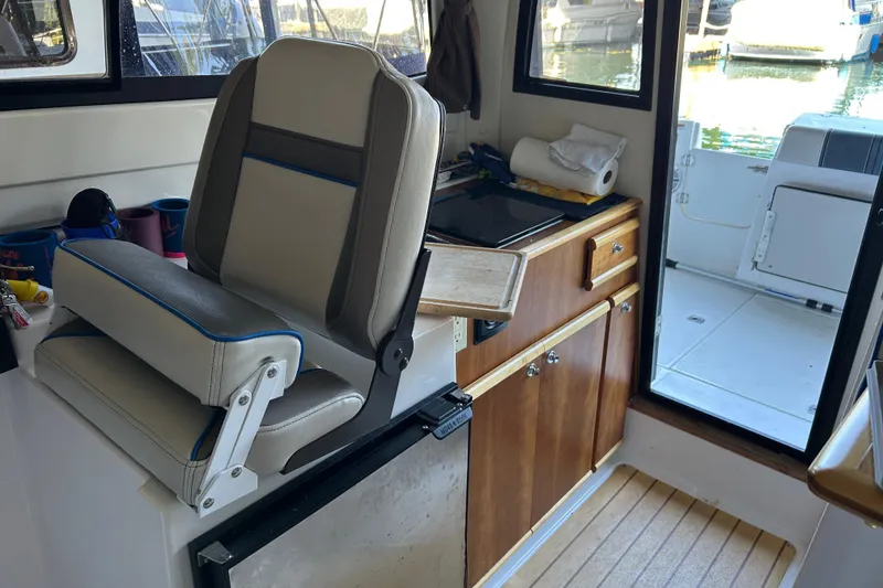 Slide: The Image of Interior of a 2017 Cutwater C-24 boat featuring a helm seat and compact kitchenette. - 13