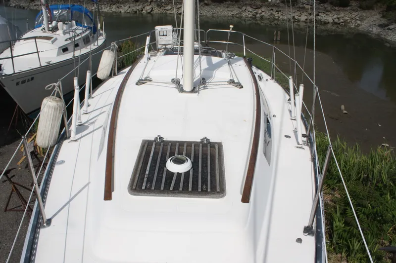 Slide: The Image of 1981 S2 9.2A sailboat deck with railing and hatch, docked near shore. - 12