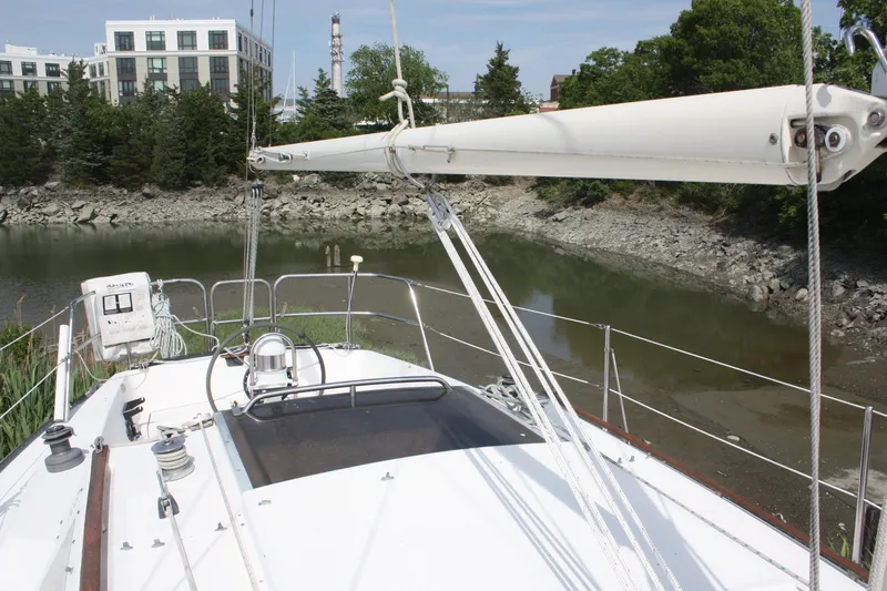 Slide: The Image of S2 9.2A sailboat from 1981 docked near a rocky shoreline with buildings in the background. - 13