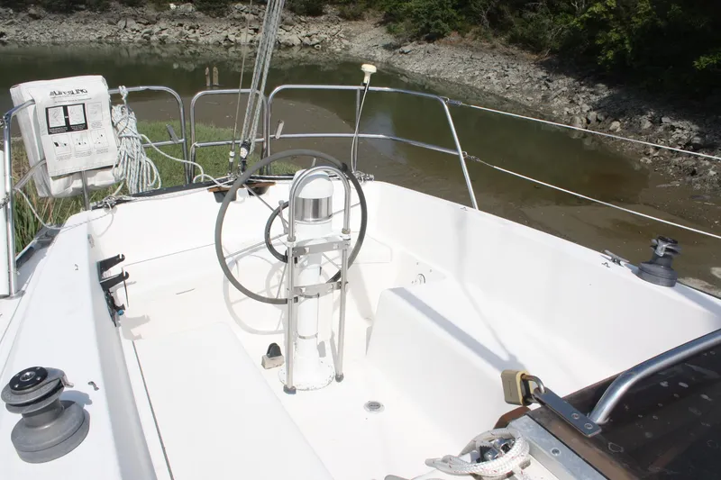 Slide: The Image of Cockpit of 1981 S2 9.2A sailboat with steering wheel and winches, docked by rocky shore. - 14